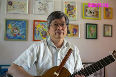 Takashi Ogawa, guitare et traverso en main devant une partie de ses dessins