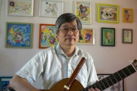 Takashi Ogawa, guitare et traverso en main devant une partie de ses dessins, photo de Stéphane Boularand (c)Bigorre.org